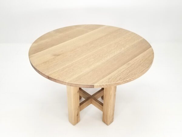 A OTTO round dining table made of wood with a cross on top.