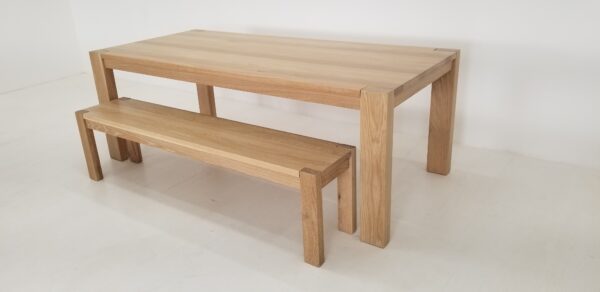 A white oak dining table with a solid white oak bench next to it.