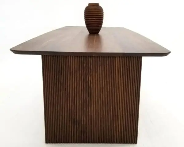 A walnut wooden table with ribbed legs and a vase on top.