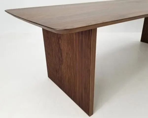 A close up of a walnut wooden table with ribbed legs.