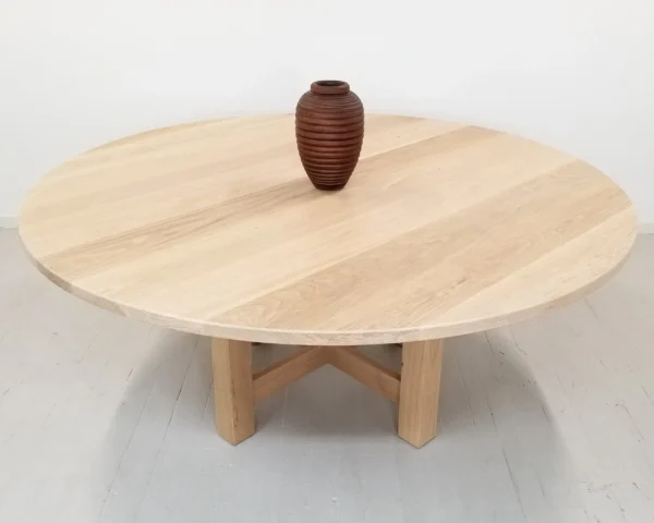 A round dining table with a vase on top of it.