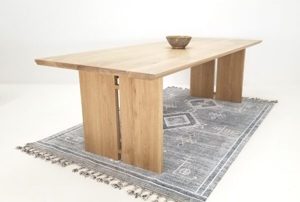 A wooden table with split panel legs and a bowl on top.