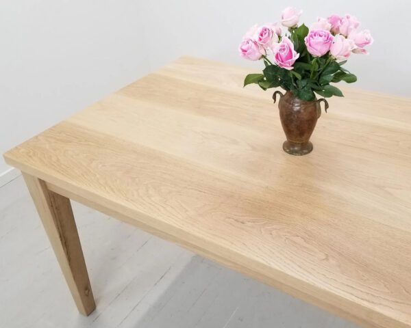 A tapered leg dining table with a vase and flowers on top of it.
