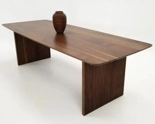 A walnut wooden table with ribbed legs and a vase on top.