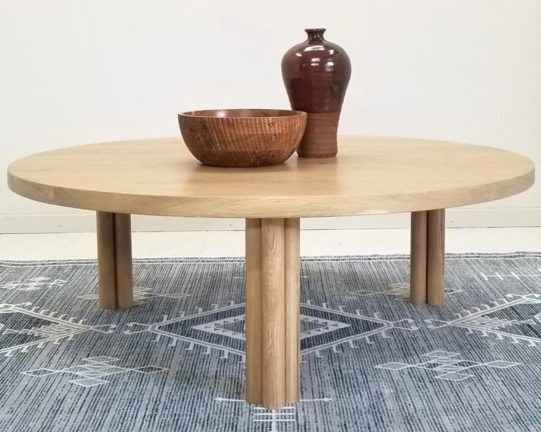 A wooden round coffee table with two vases on top of it.
