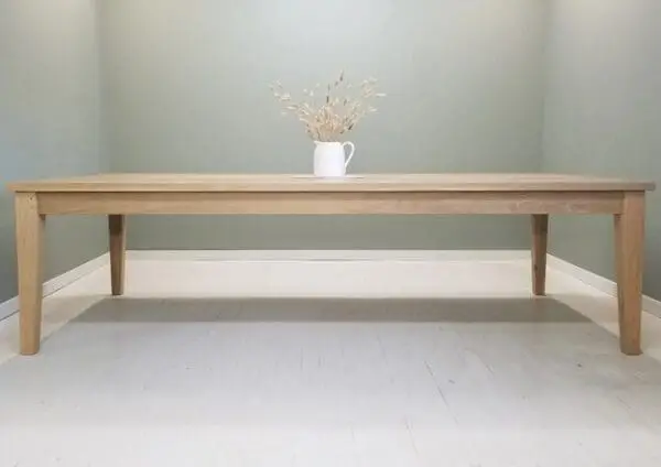 A tapered leg dining table with a vase on top of it.