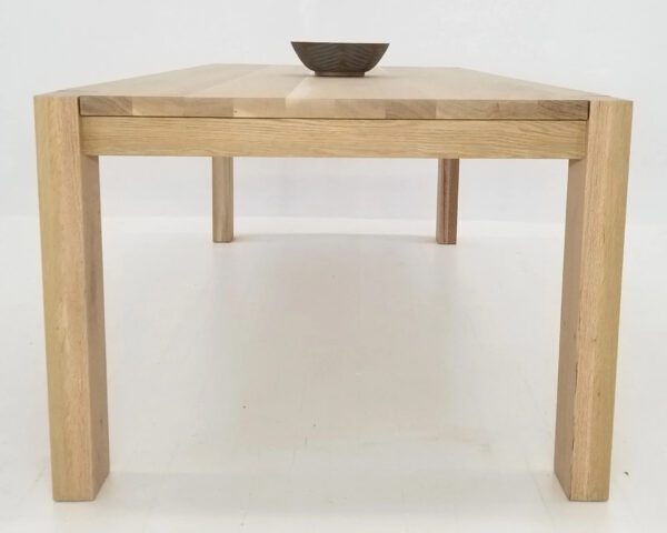 A wide leg parsons dining table with a bowl on top.