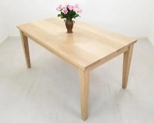 A tapered leg dining table with a vase and flowers on top of it.