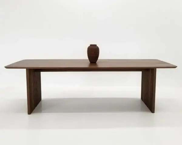 A walnut wooden table with ribbed legs and a vase on top.