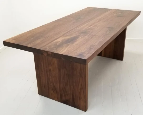 A walnut wooden table with two legs and no one around it.