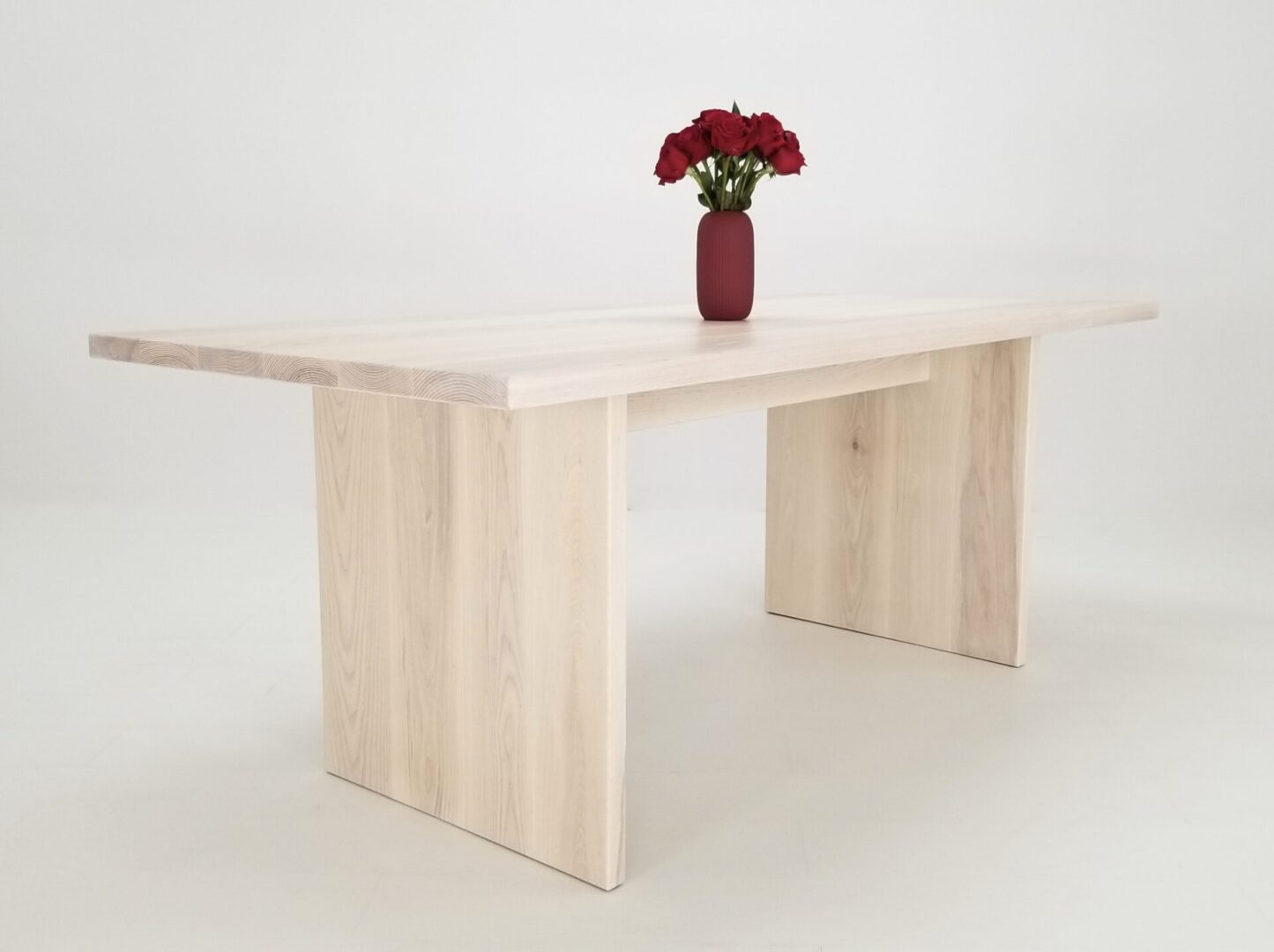 A white wood LILY 1.5 panel dining table with flowers in a vase.