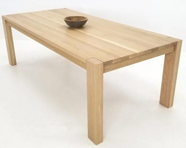 A wide leg parsons dining table with a bowl on top.