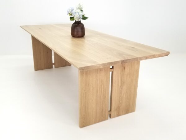 A DIVI Dining Table with Split Panel Legs, showcasing a beautiful vase on top.