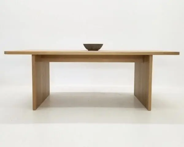 A TIAN Dining Table with Rounded Corners and a bowl on top in front of a white background.