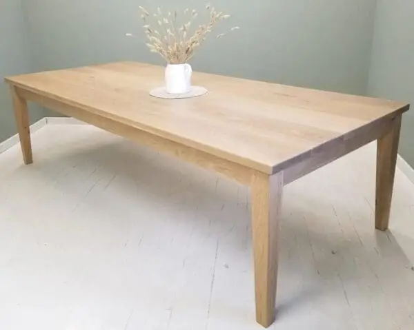 A tapered leg dining table with a vase and flowers on top of it.