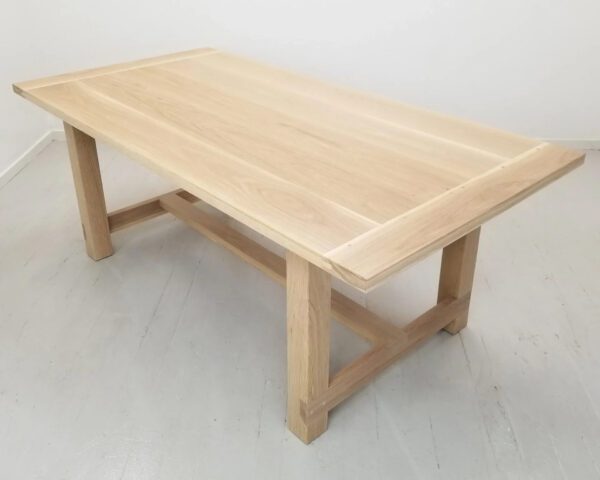 A natural white oak trestle dining table.