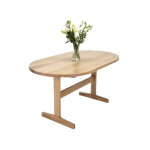 A BANQ Oval Top Trestle Dining Table with flowers in a vase.