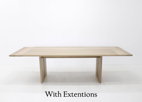 A wooden table with split panel legs and table extentions.