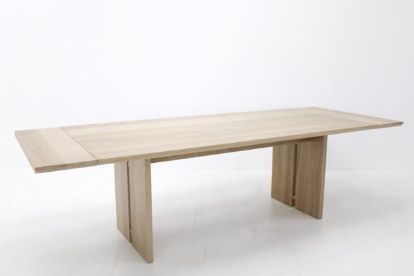 A wooden table with split panel legs and table extentions.