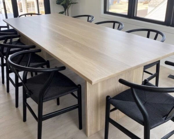 A large LILY 1" Thick dining table with black chairs.