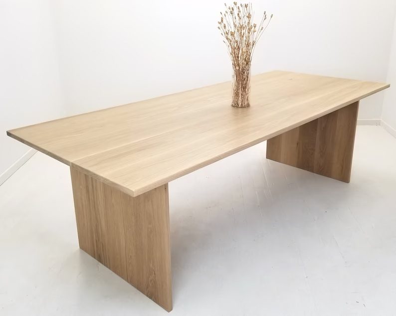 White oak panel table with vase on top.