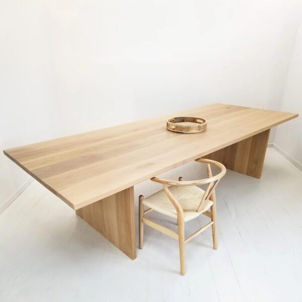White oak panel table with a chair next to it.