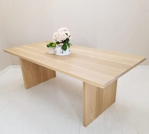 White oak panel dining table with vase and flowers on top.