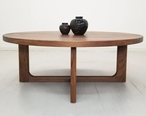 A CARY Round Cross Leg Coffee Table with a vase on top.