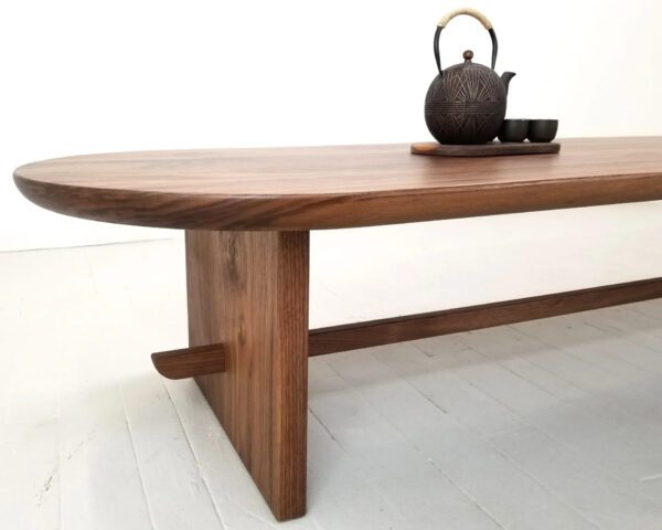 A close up of a trestle coffee table with a tea kettle on top.