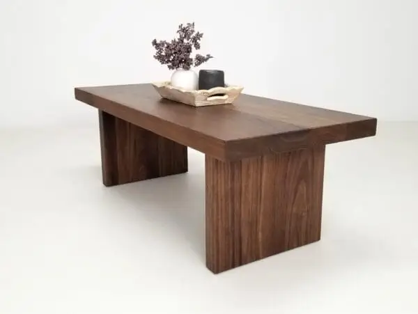 A wooden panel coffee table with flowers and a candle on top of it.