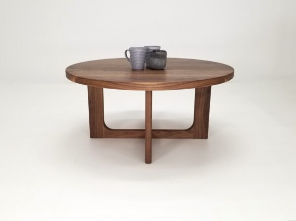 A CARY Round Cross Leg Coffee Table, adorned with two mugs.