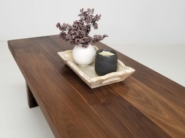 A wooden panel coffee table with flowers and a candle on top of it.