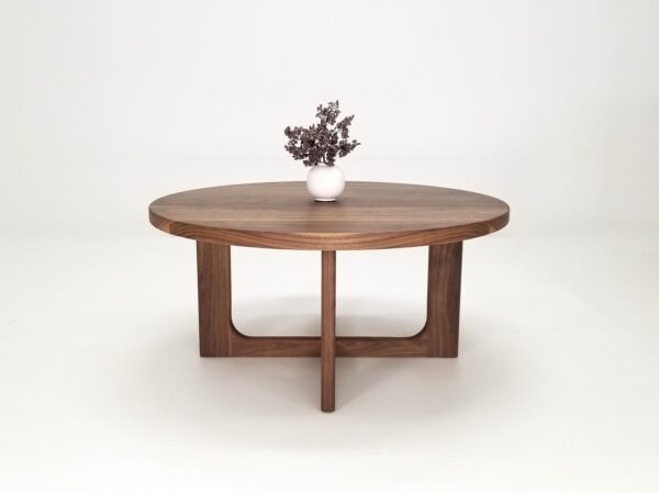 A CARY Round Cross Leg Coffee Table with a flower centerpiece.