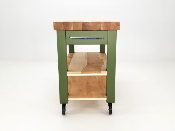A side view of a green butcher block kitchen island with shelves underneath it.