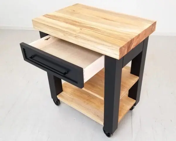 A black butcher block kitchen island with shelves underneath it.