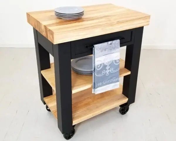 A black butcher block kitchen island with shelves underneath it.