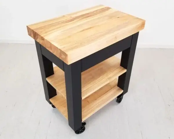 A black butcher block kitchen island with shelves underneath it.