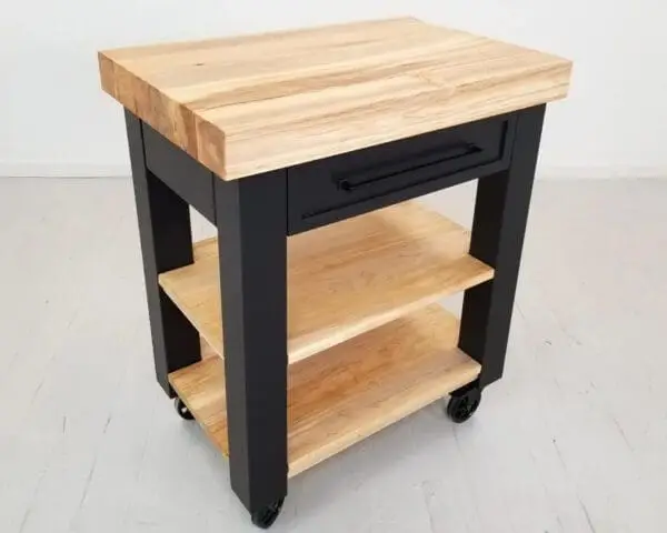 A black butcher block kitchen island with shelves underneath it.