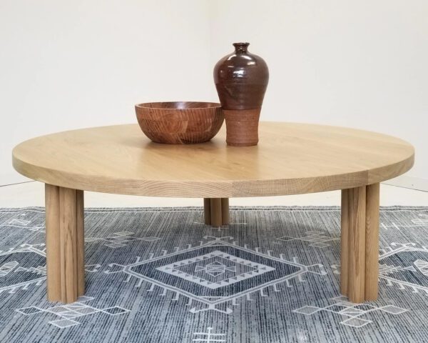 Our white oak BEAU coffee table with cylinder legs and a vase on top of it.