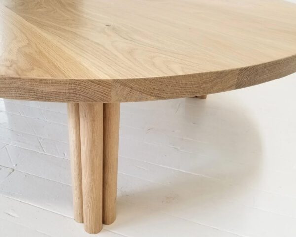 A close up of a white oak BEAU coffee table with cylinder legs.