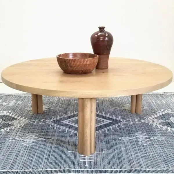 Our white oak BEAU coffee table with cylinder legs and a vase on top of it.