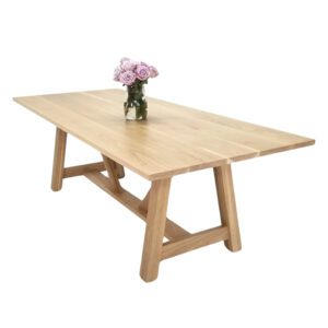 An a-line trestle base dining table with a vase on top.