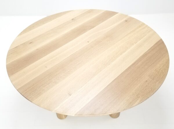 A close up of a natural white oak round dining table.