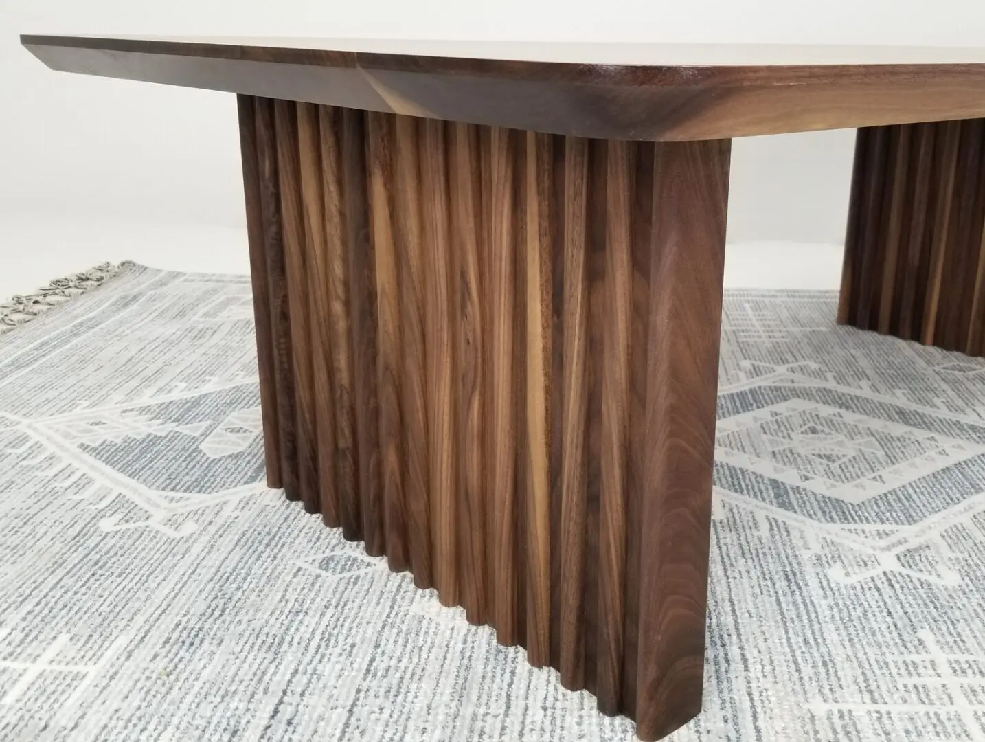A close up of a walnut coffee table with tambour inspired legs.