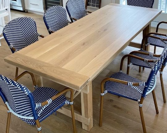 A wooden dining table with blue chairs, captured perfectly in client photos.