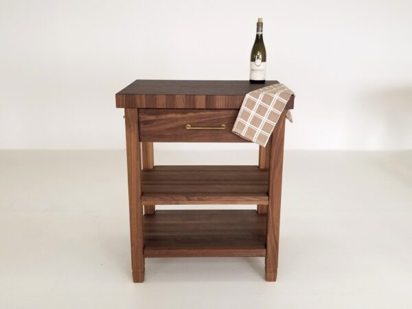 A walnut end-grain butcher block kitchen island with a bottle on top.