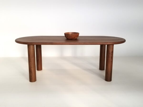 A oval walnut dining table with a bowl on top.