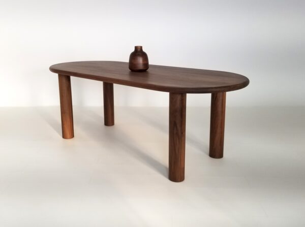 A oval walnut dining table with a vase on top.
