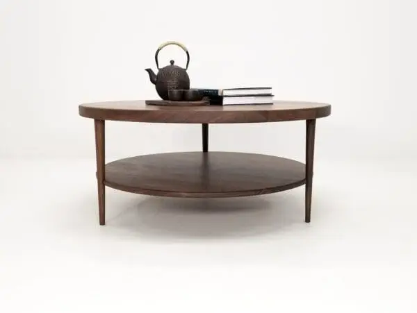 A walnut coffee table with three tapered legs and a tea set on top of it.