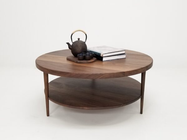 A walnut coffee table with three tapered legs and a tea set on top of it.